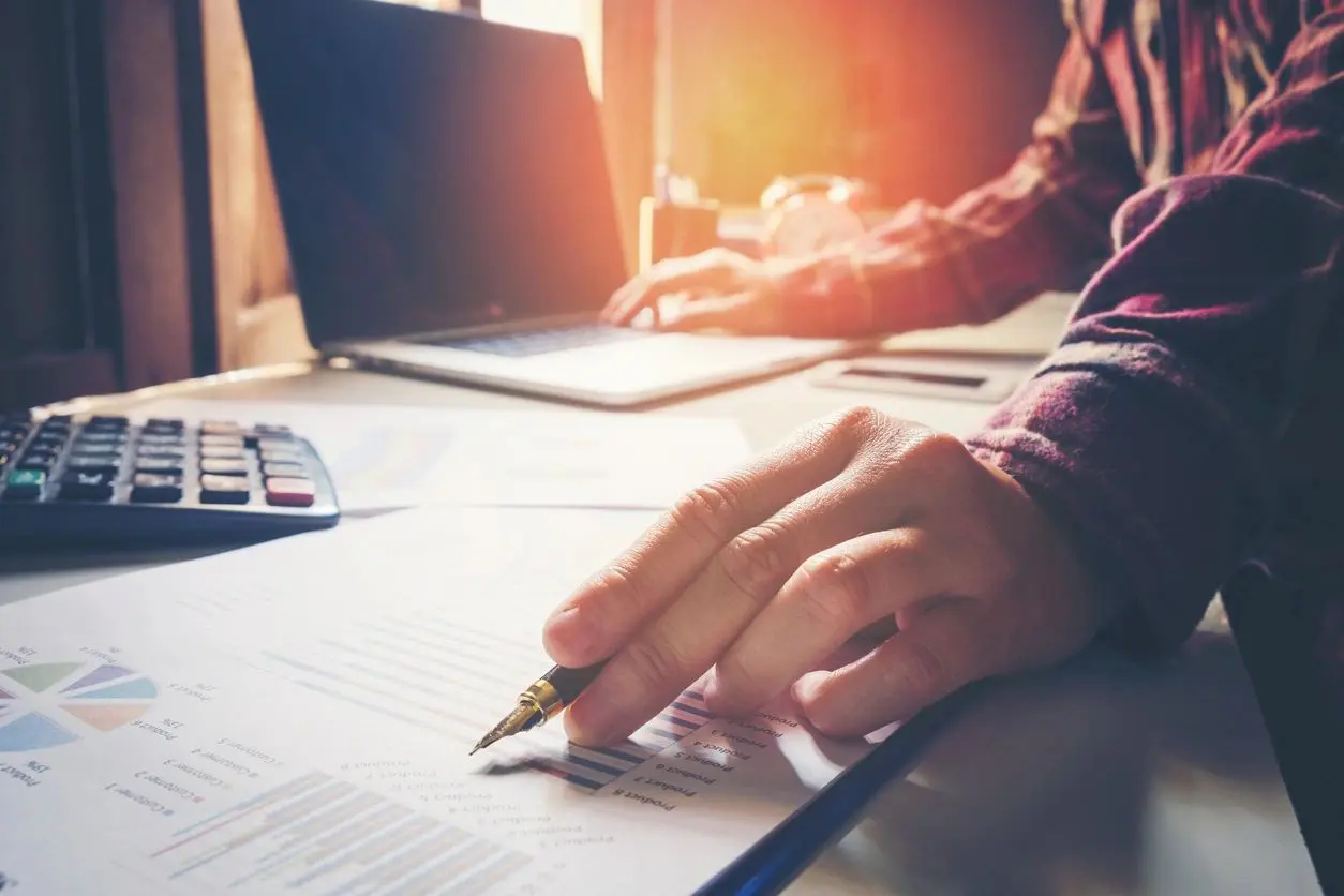 A person writing on paper with a pencil.