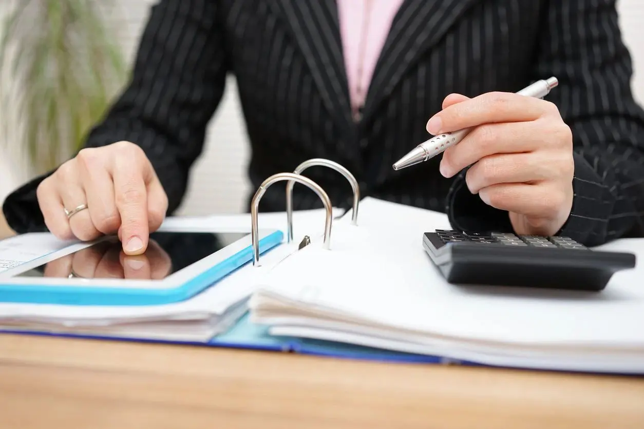 A person sitting at a table with papers and a pen.